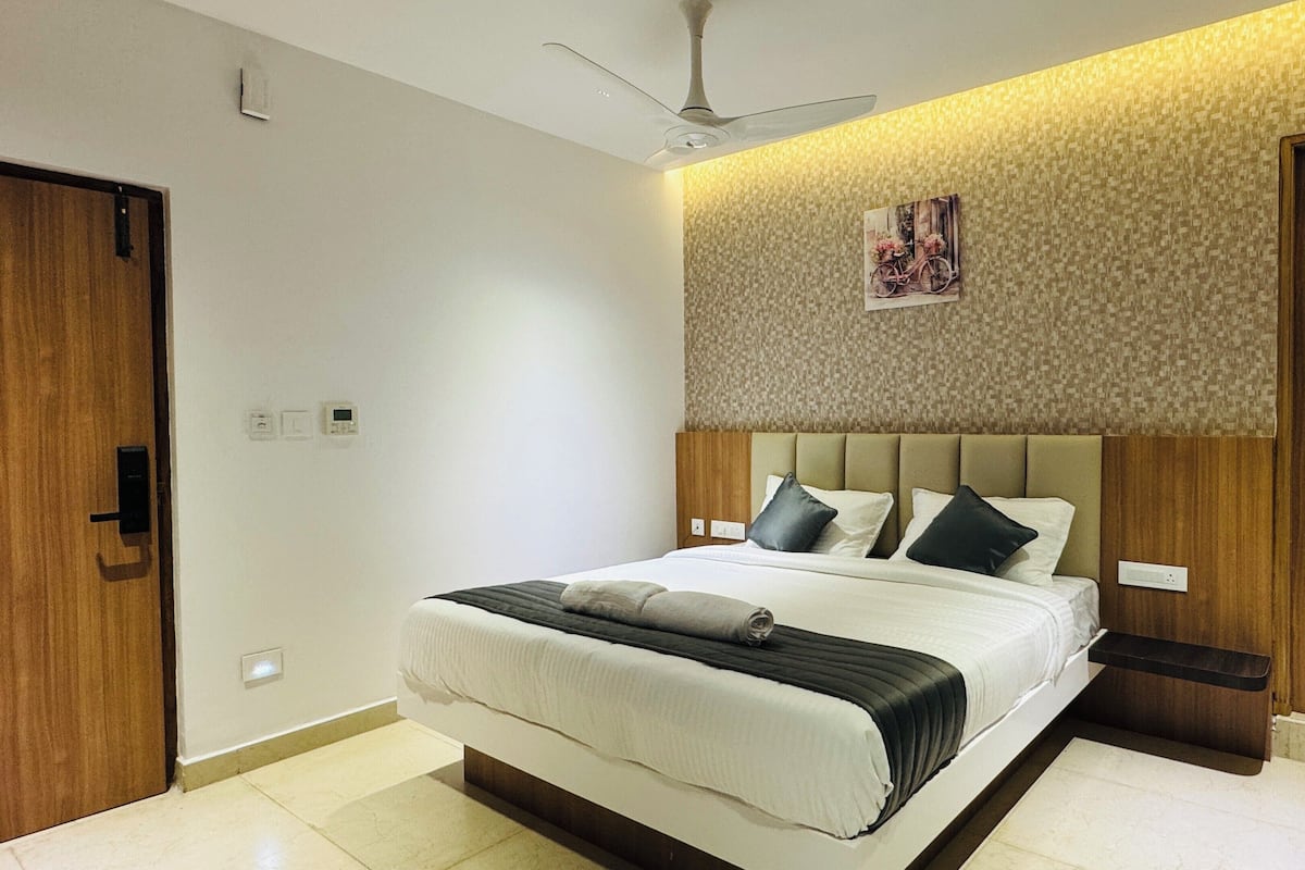A modern bedroom with a large bed, a ceiling fan, and a patterned wall.