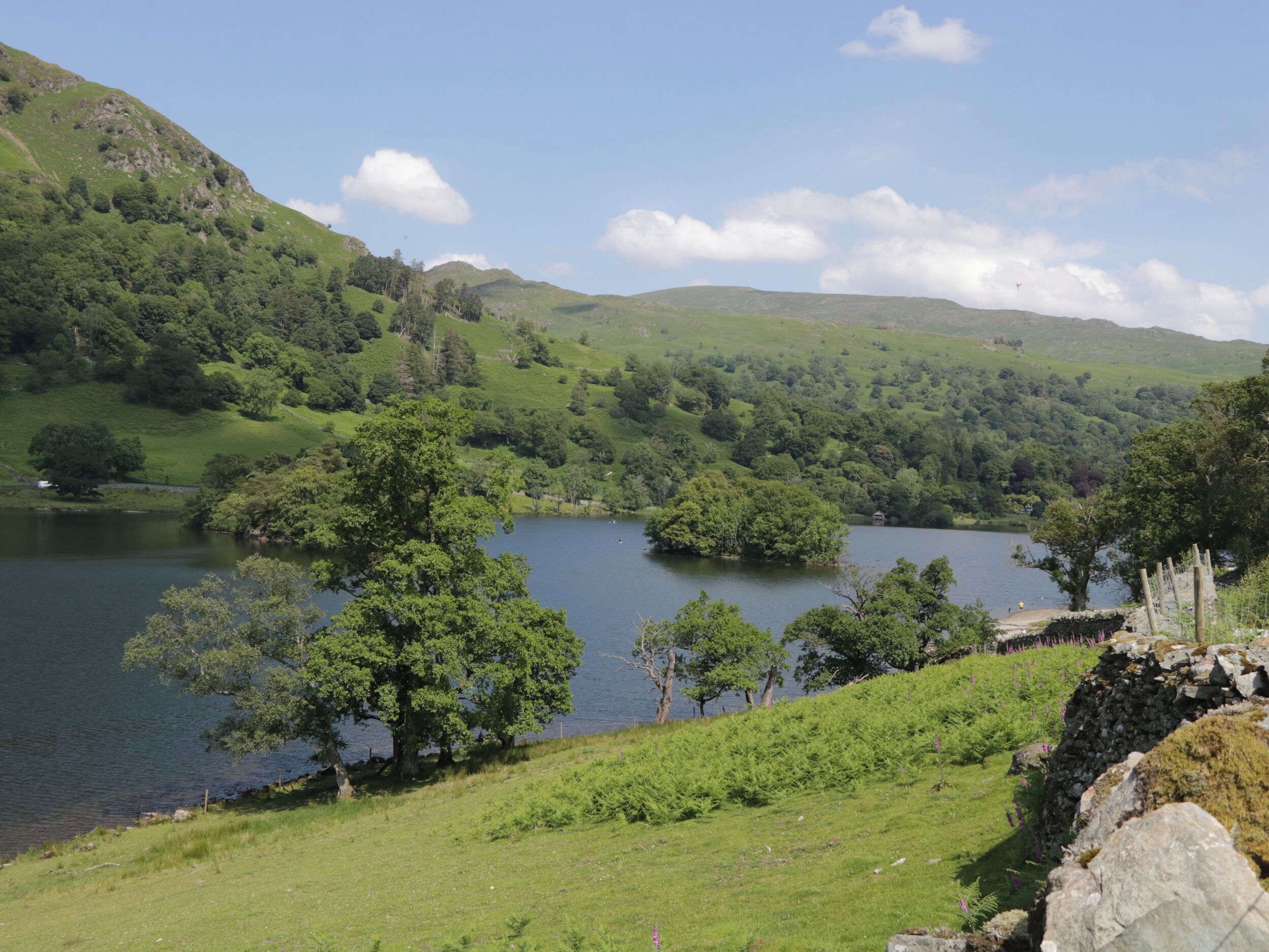 A serene lake surrounded by lush green hills and trees.