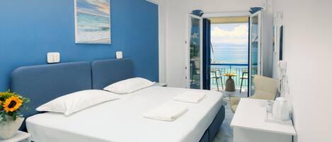 Una habitación de hotel moderna con una cama grande, un escritorio y un balcón con vistas al mar.