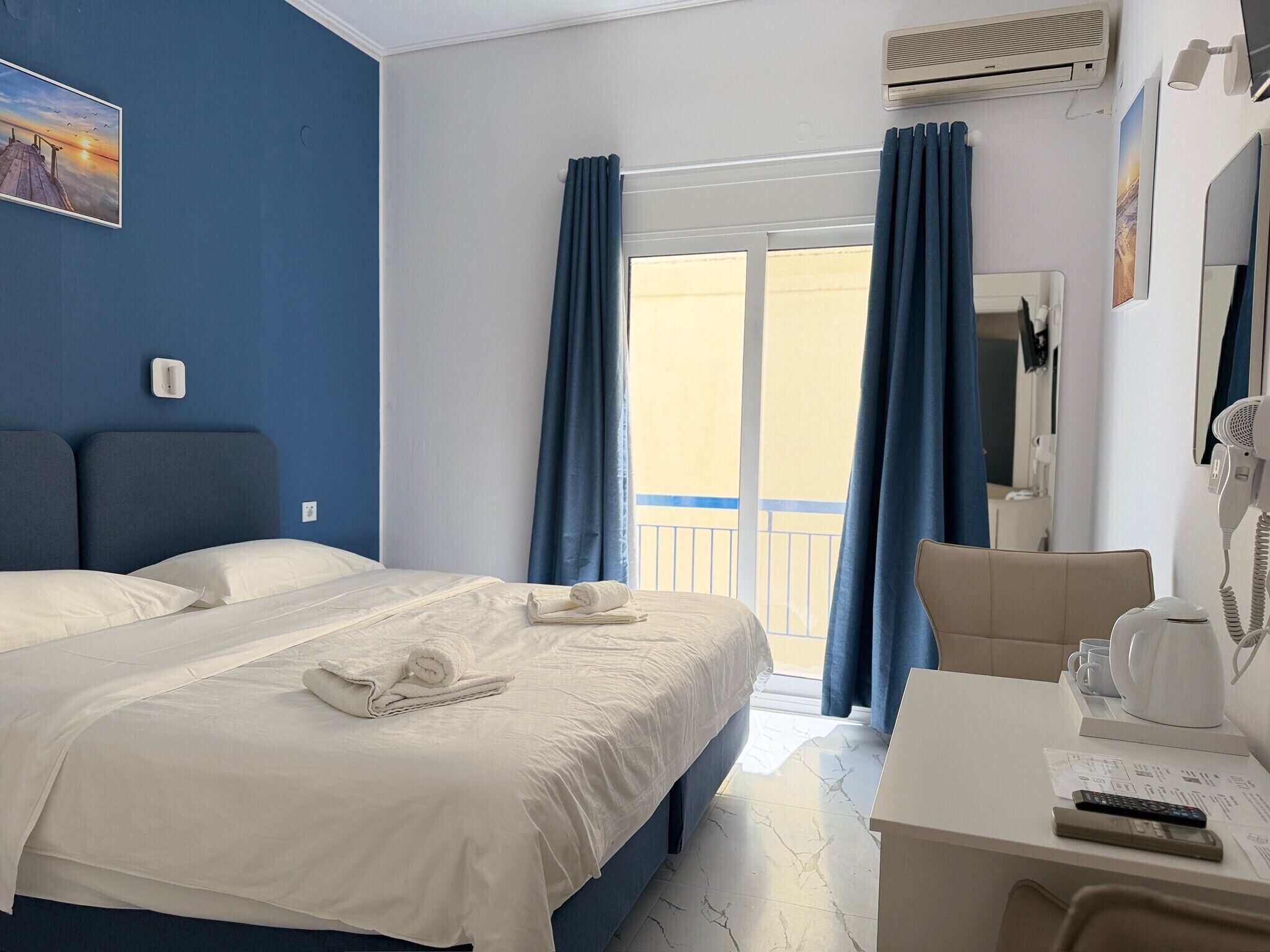 Ein Hotelzimmer mit einem Bett, einem Schreibtisch mit Stuhl, einem Fön und einem Fenster mit Vorhängen.