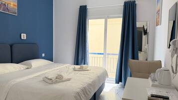 Ein Hotelzimmer mit einem Bett, einem Schreibtisch mit Stuhl, einem Fön und einem Fenster mit Vorhängen.