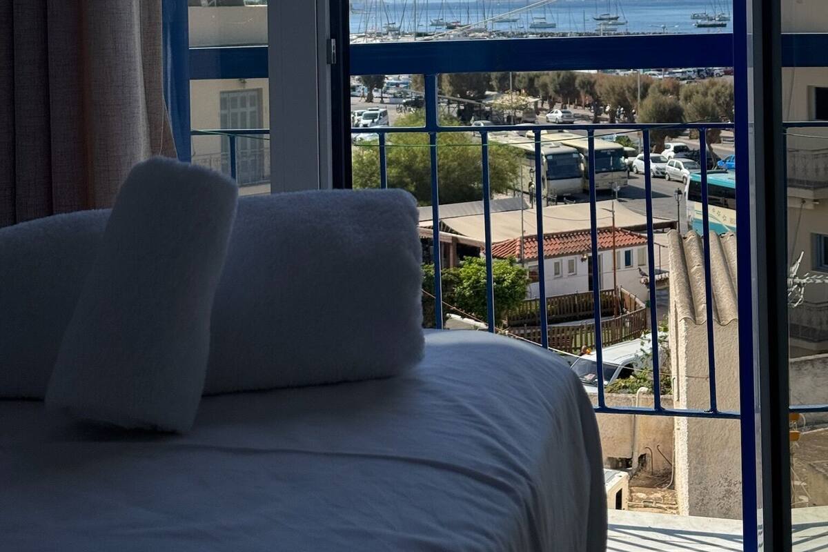Et hotelværelse med en seng, udsigt til en lystbådehavn og en bro i det fjerne.