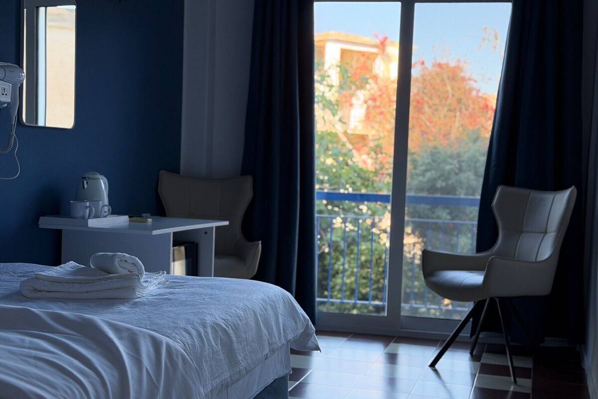 Et hotelværelse med seng, skrivebord, stol og udsigt til det fri.