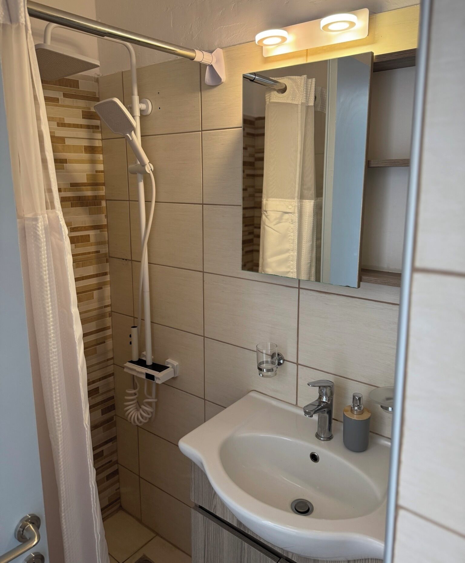 A modern bathroom with a shower, a sink, and a mirror.