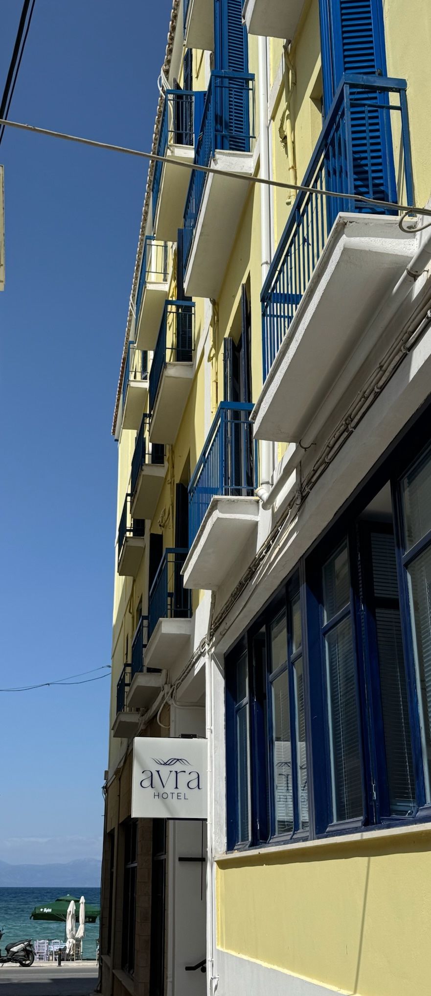 Un edificio de hotel con contraventanas azules y un letrero que dice "Avra Hotel".