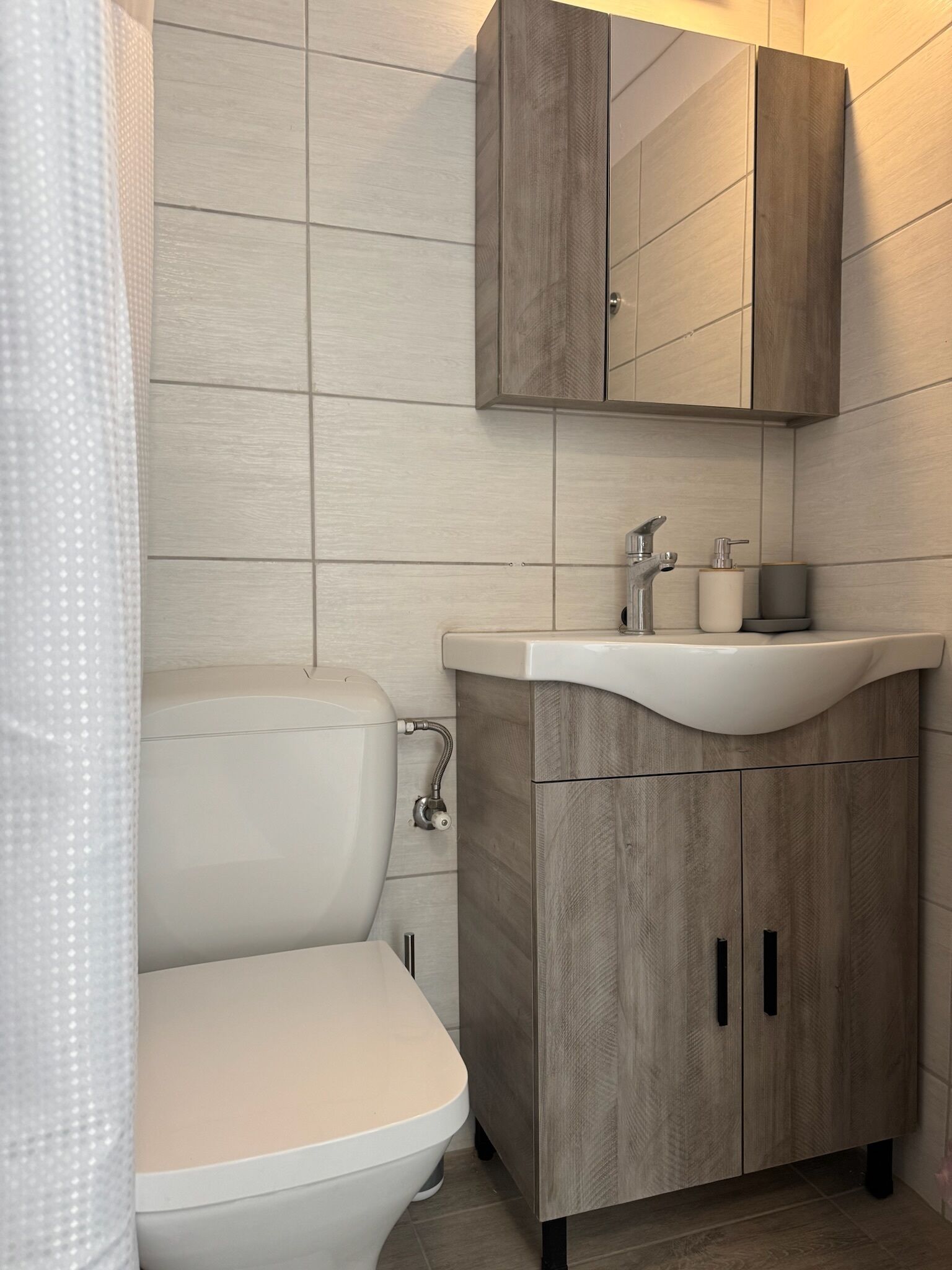 Een moderne badkamer met toilet, wastafel en houten kasten.