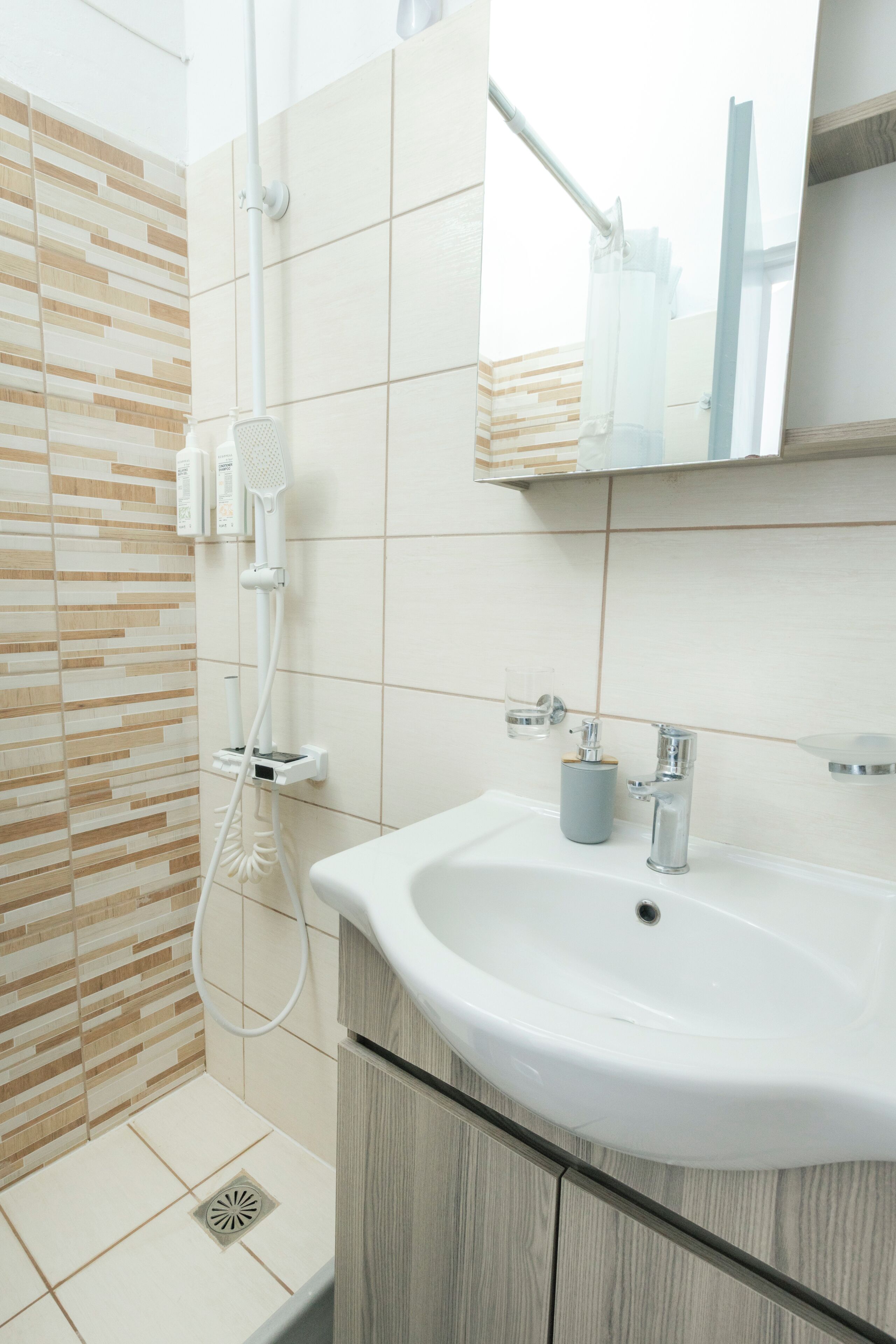 Une salle de bain avec une douche, un lavabo et un miroir.