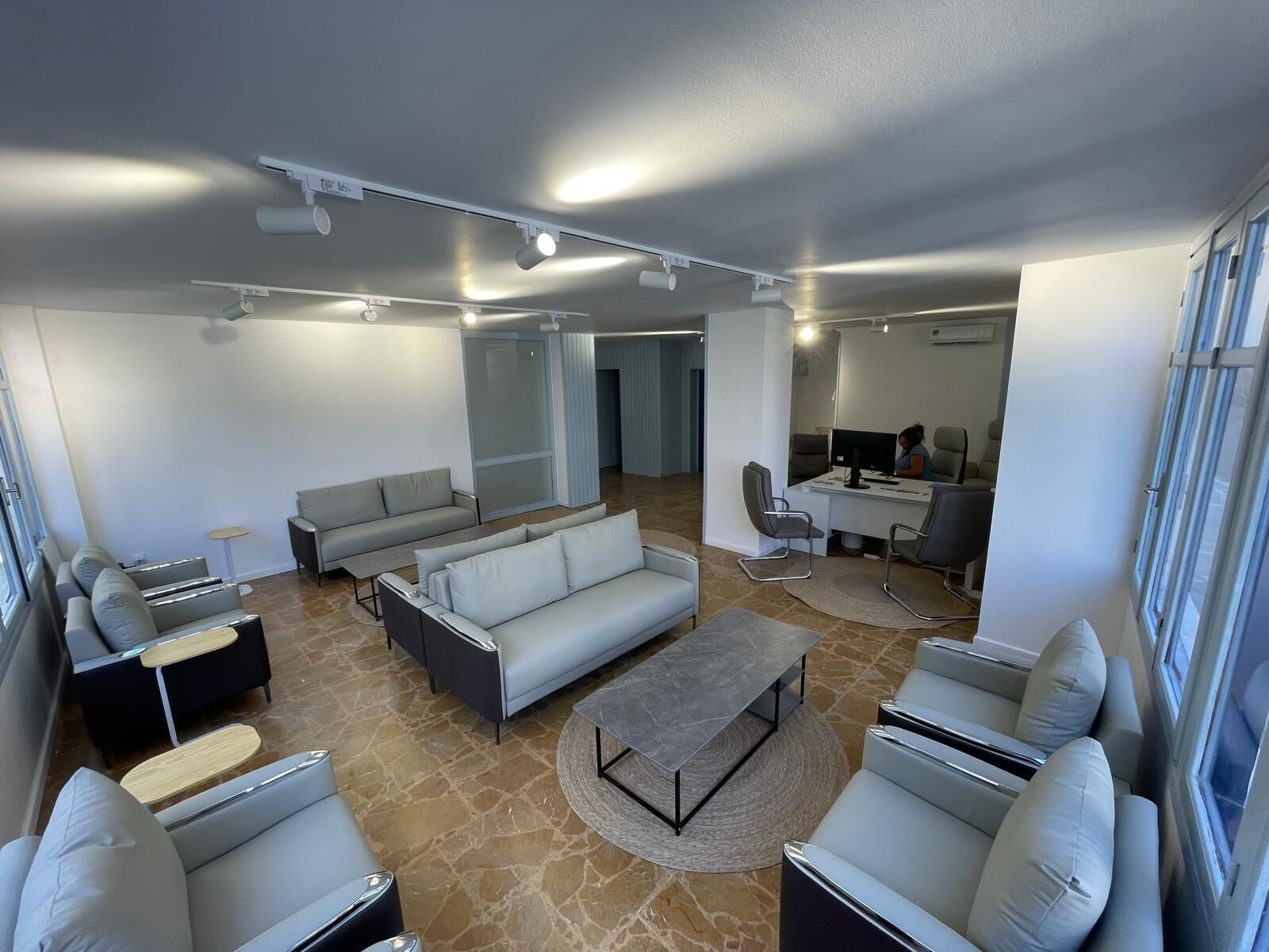 Uma sala de estar moderna com um sofá, uma mesa de centro e uma escrivaninha com um computador.