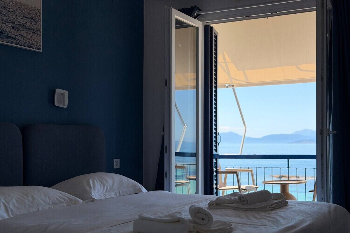 Et hotelværelse med seng, havudsigt og en balkon med havemøbler.