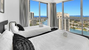 A hotel room with two beds, large windows, and a view of the city and water.