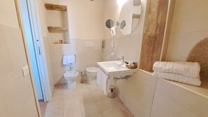 A bathroom with a toilet, sink, and mirror. There is a towel rack and a trash can. - Cozy B&B room on two levels ideal for 2 or 3 people (Belmonte Calabro)