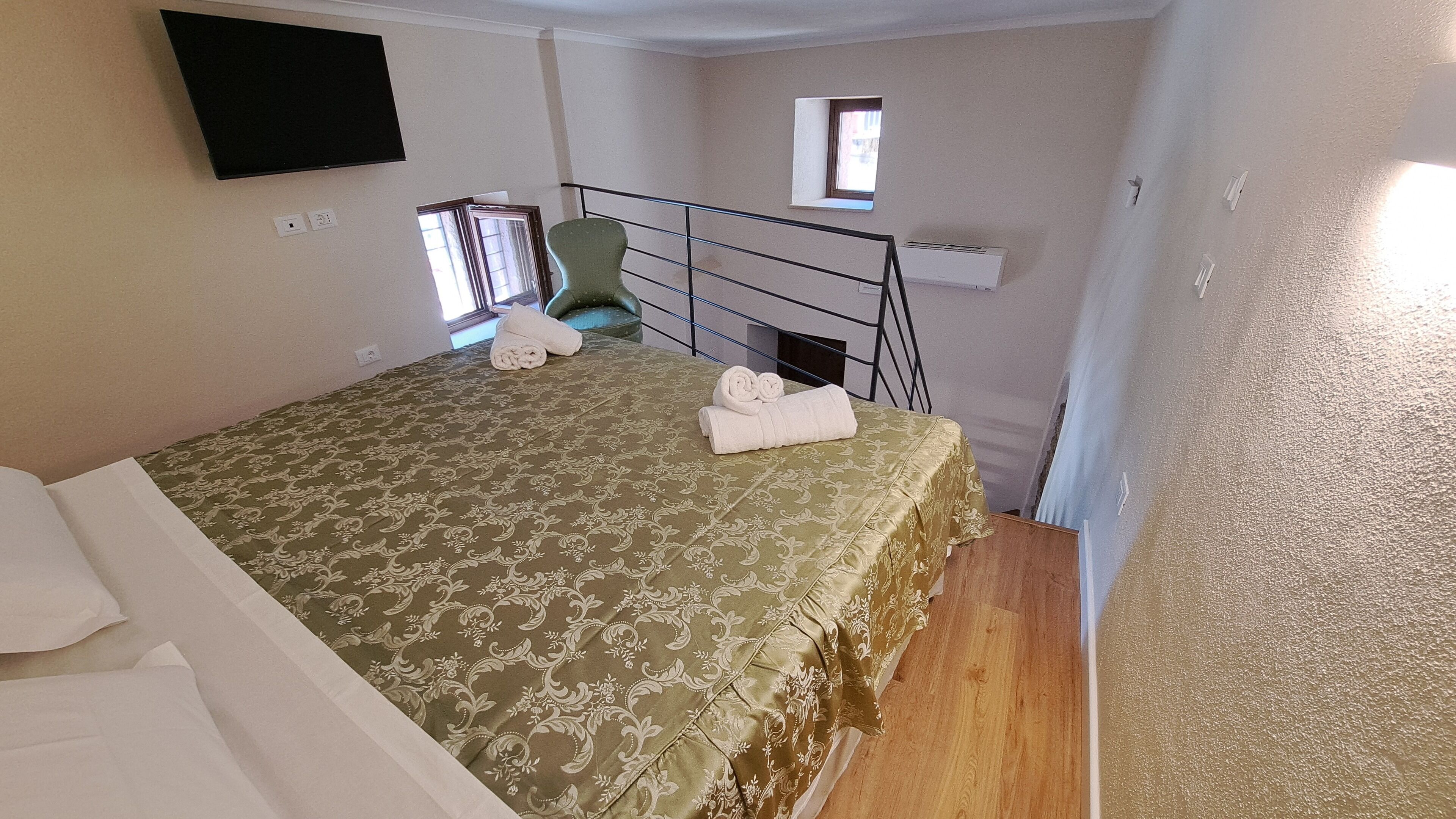 Un dormitorio con cama, una silla, un televisor y una ventana.