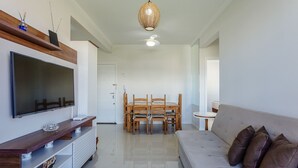 A modern living room with a flat-screen TV, wooden dining table, and a sofa. - Cozy Apartment 5 Mi From the Beach, Floripa Ece104 (Florianópolis)
