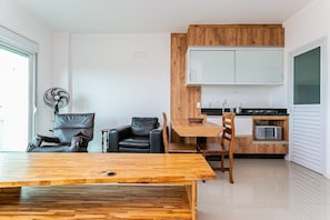 Un espacio habitable compacto con una mesa de comedor, dos sillas, un sofá, un ventilador y una kitchenette.