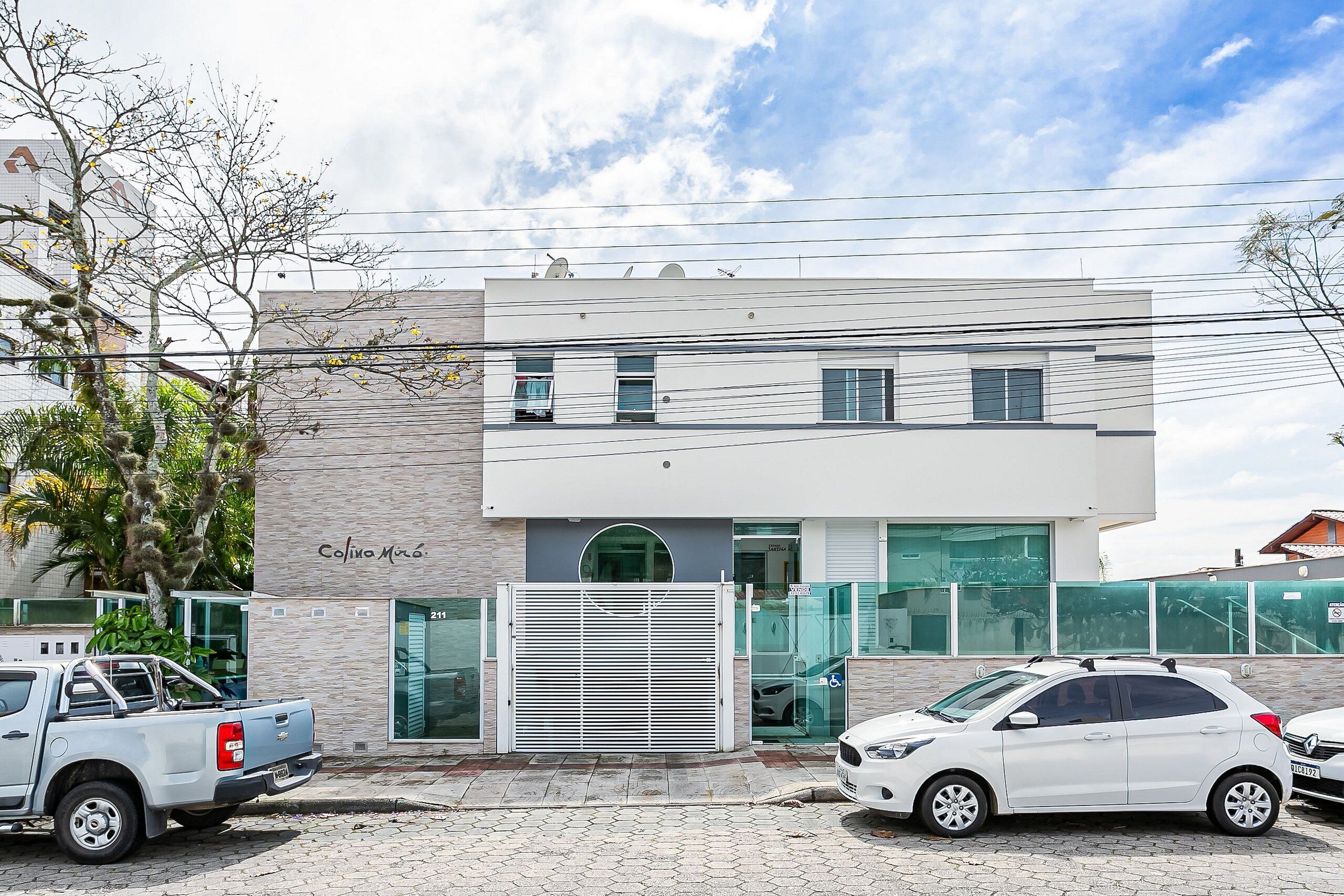 A modern building with a flat roof, a gated entrance, and a sign that reads 'Colina Mar'.