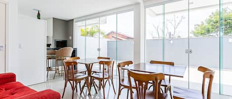 Un comedor moderno con mesas y sillas de madera, un sofá rojo y ventanas amplias que ofrecen vistas al exterior.