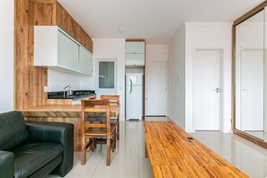 Una cocina moderna con armarios de madera, una zona de comedor con mesa y sillas de madera, y un sofá de cuero negro.