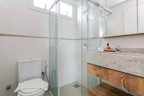 Une salle de bain moderne avec une douche à parois de verre, des toilettes et un comptoir en granit doté d’un distributeur de savon.