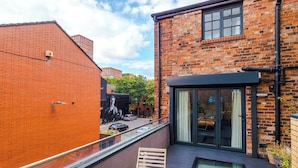 A rooftop terrace with a pool, a brick building, and a glass door entrance.