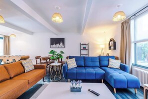 Una sala moderna con un sofá seccional azul, un sofá marrón, y una zona de comedor con mesa y sillas.