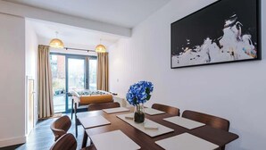 A conference room with a long table, chairs, a vase with blue flowers, and a large abstract painting on the wall.