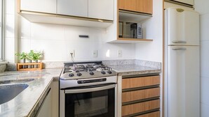 A kitchen with a gas stove, oven, wooden cabinets, and a built-in microwave. - Charming Apartment in Downtown Floripa Edc402 (Florianópolis)