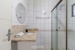 A bathroom with a marble sink, a mirror, a towel, and a glass shower enclosure. - Charming Apt With Balcony and Sea View Edj0410 (Florianópolis)