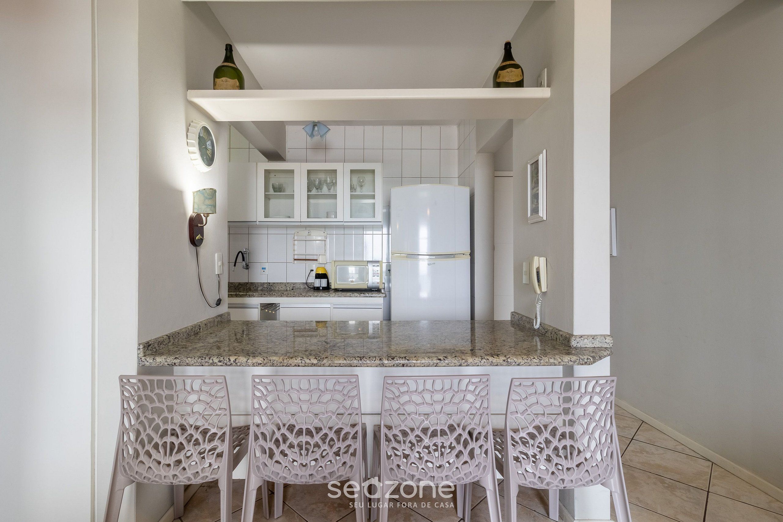 A kitchen with a central island, white cabinets, a refrigerator, and a microwave.