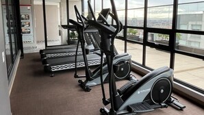 A gym with cardio machines and large windows offering a city view. - City-view apartment in Chapinero – fast WiFi, 24h security, gym & coworking (Bogotá)