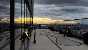 A rooftop terrace with a city view, glass railings, and a winding pathway. - City-view apartment in Chapinero – fast WiFi, 24h security, gym & coworking (Bogotá)
