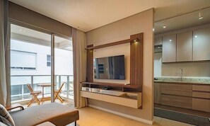 Un appartement moderne doté d’un balcon, d’un coin repas, d’une cuisine et d’un téléviseur fixé au mur.