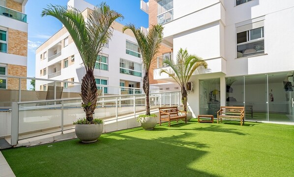 Un bâtiment moderne doté de balcons, d’une pelouse artificielle et de plantes en pot.