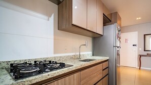 A modern kitchen with a gas stove, stainless steel refrigerator, wooden cabinets, and a granite countertop. - Apt Close to Beach & Floripa Shopping [eaz305] (Florianópolis)