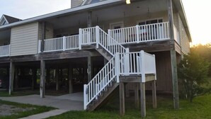 Ein zweistöckiges Haus mit überdachter Veranda und einer Treppe, die zum oberen Stock führt.