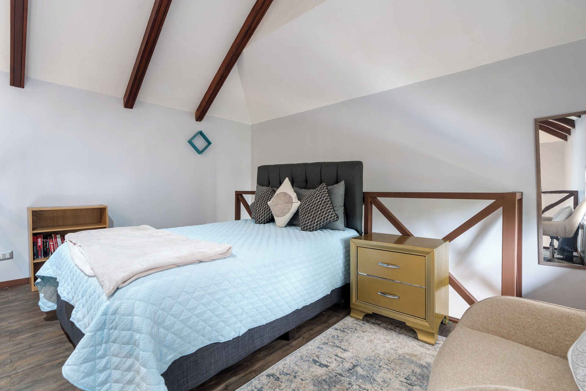 A bedroom with a bed, bedside table, and a small bookshelf.