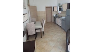 Une cuisine de taille réduite comprenant une table à manger, des chaises et les appareils électroménagers de base.