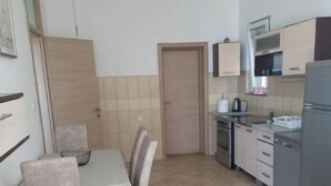 Une cuisine de taille réduite comprenant une table à manger, des chaises et les appareils électroménagers de base.