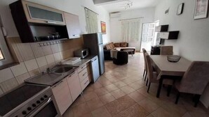 Une cuisine compacte équipée d’une cuisinière, d’un four à micro-ondes et d’un évier. Un coin repas avec une table et des chaises est également disponible.