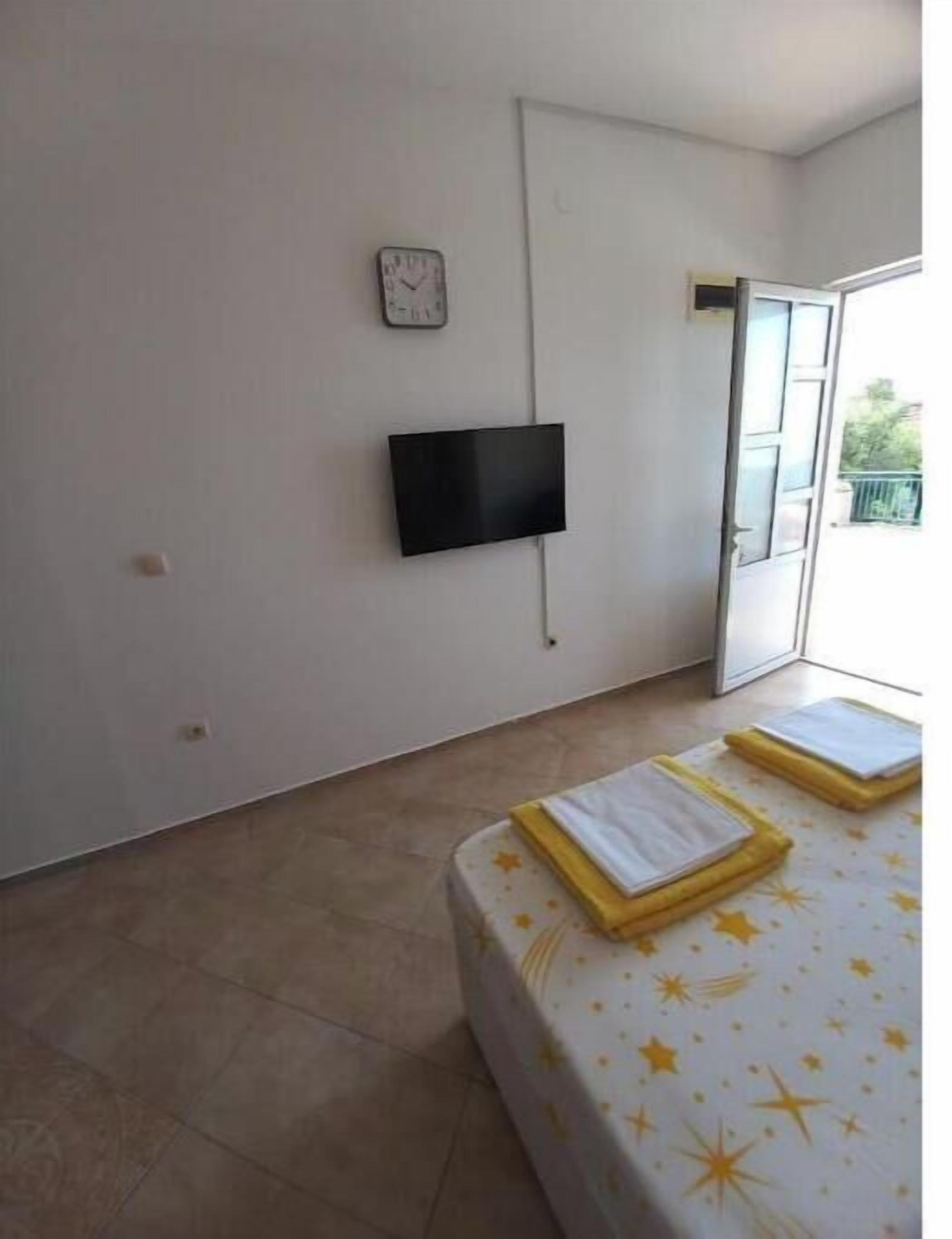 Une chambre comprenant un lit, un téléviseur à écran plat fixé au mur, une porte donnant sur un espace extérieur et une fenêtre.