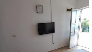A bedroom with a bed, a television on the wall, and a window.