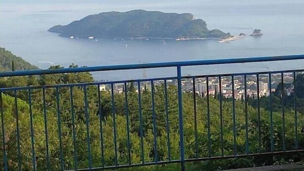 A coastal view with a small island, a bridge, and a cityscape in the distance.