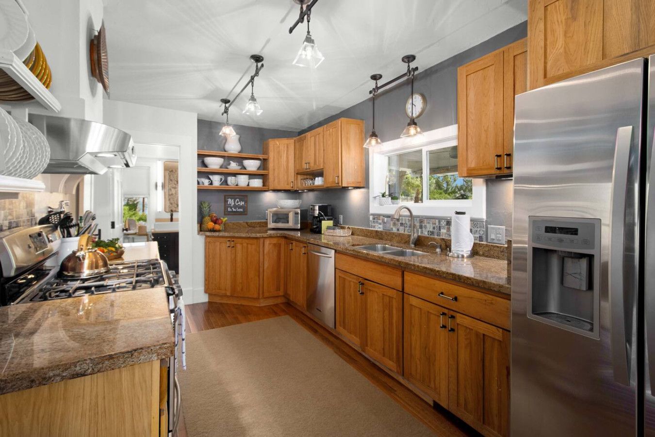 A modern kitchen with wooden cabinets, stainless steel appliances, and pendant lighting.