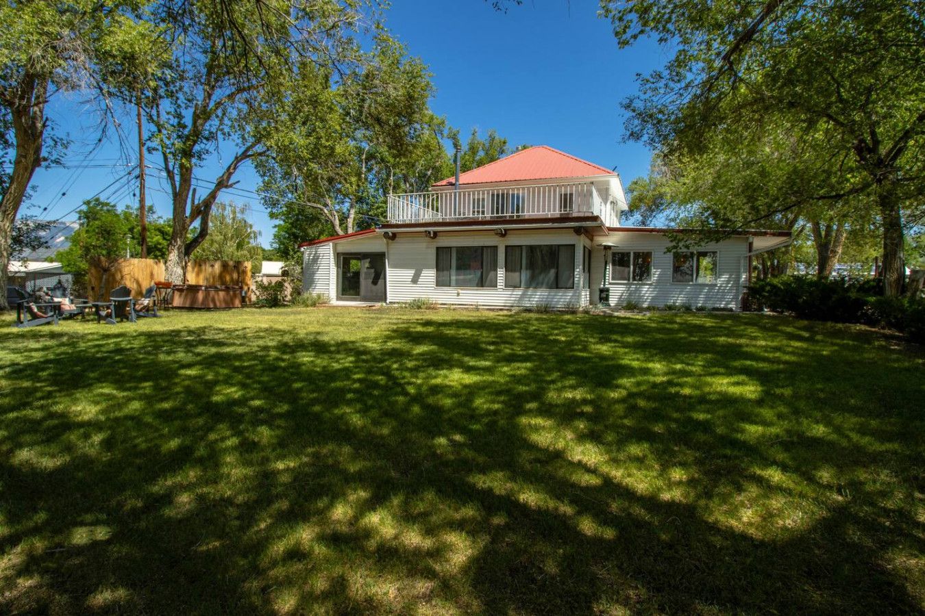 A two-story house with a red roof, a covered porch, and a well-maintained lawn.