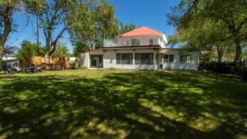 A two-story house with a red roof, a covered porch, and a well-maintained lawn.