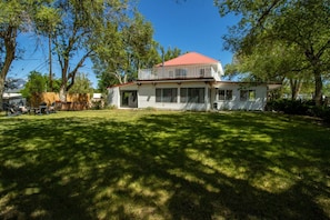 A two-story house with a red roof, a covered porch, and a well-maintained lawn.