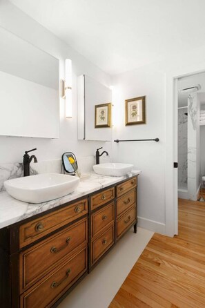 A modern bathroom with two white sinks, a wooden vanity, and a large mirror.