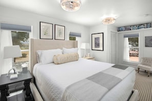 A hotel room with a large bed, a desk, a chair, and a bookshelf.