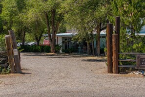 A gravel driveway leading to a gated area with a house in the background.