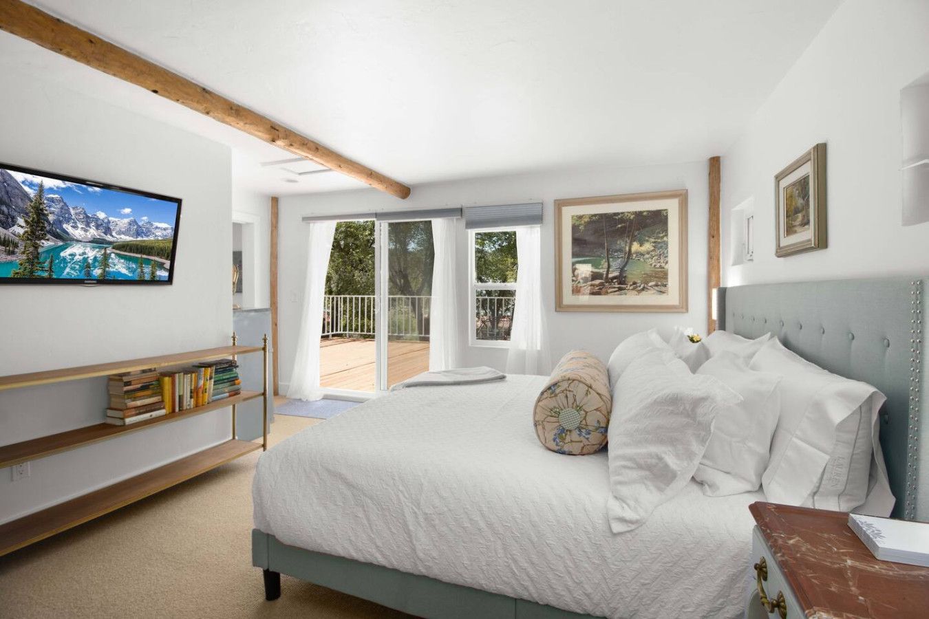 Une chambre à coucher avec un lit, une bibliothèque, une grande fenêtre et une vue sur l’extérieur.