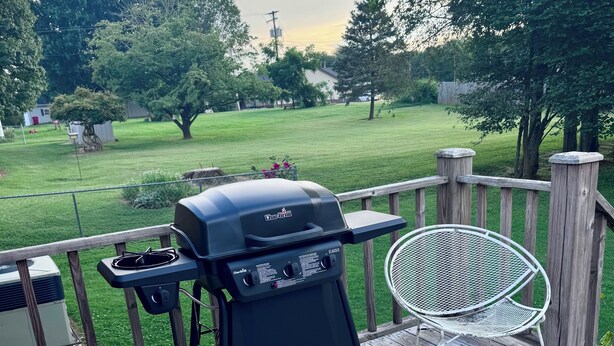 A wooden deck with a grill and a metal chair. - Terry Townhouse Two (Cave City)